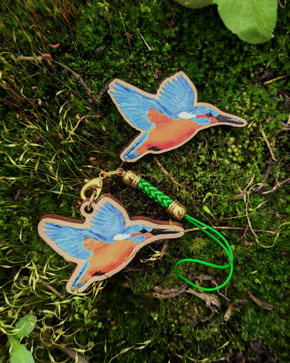 A wooden pin and charm of a kingfisher on green moss.