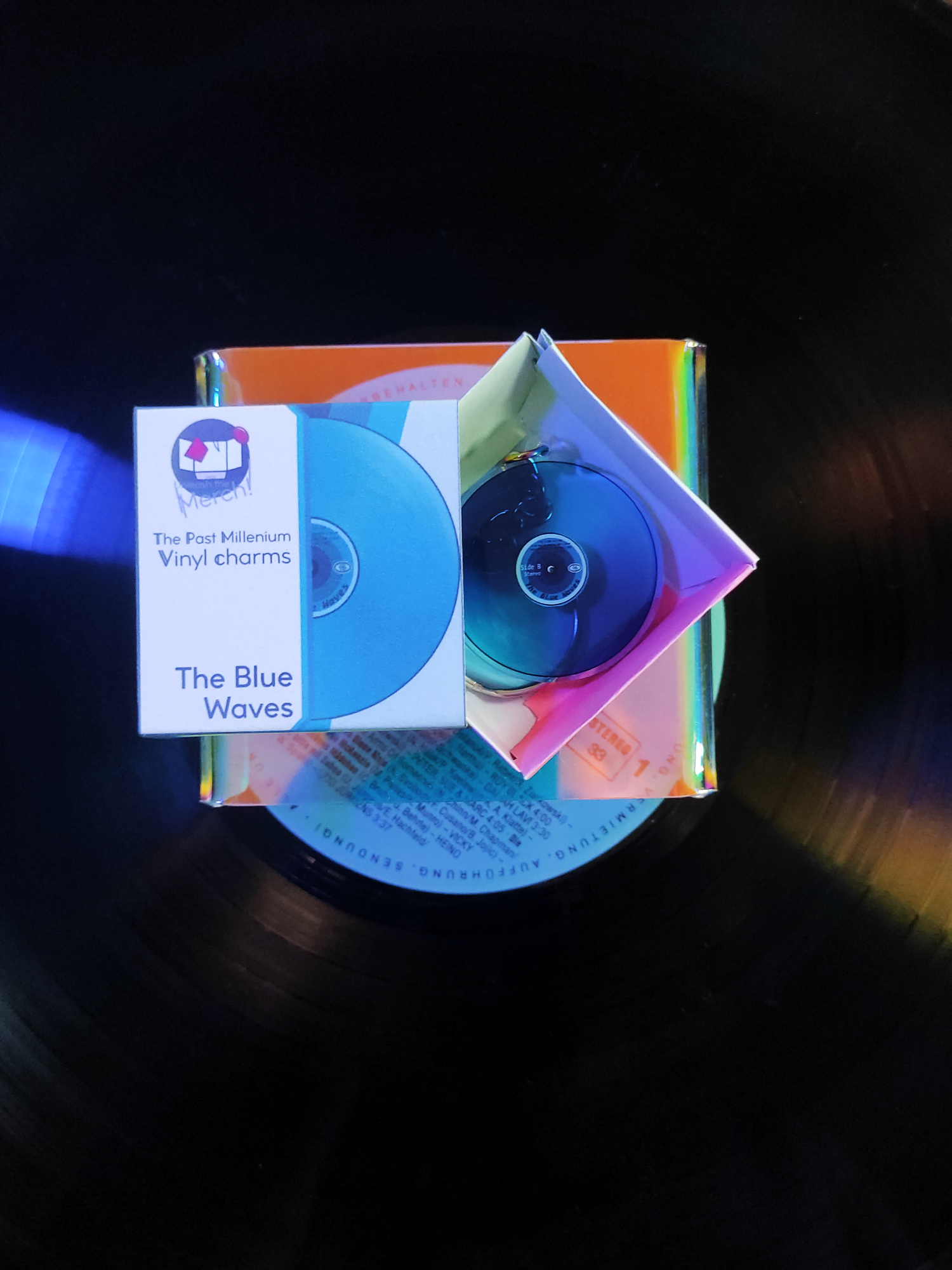 Blue vinyl record with packaging and a box on a dark surface