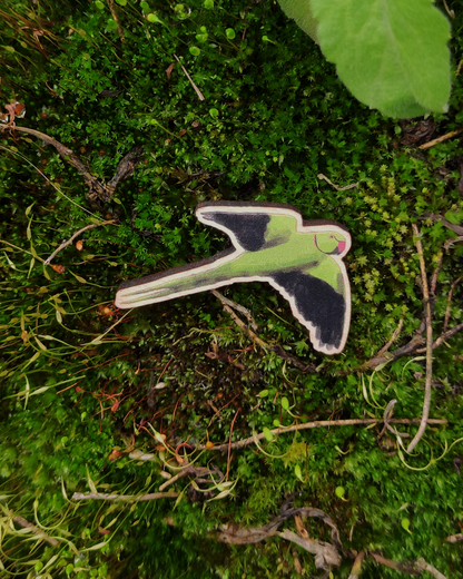 Wooden pin of the bird rose-ringed parakeet on a mossy background